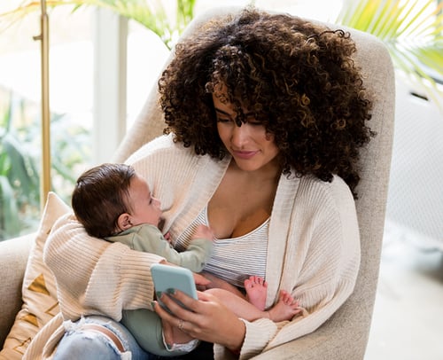 Nursing mother with baby using Babyscripts postpartum resources on app Nursing mother with baby using Babyscripts postpartum resources on app