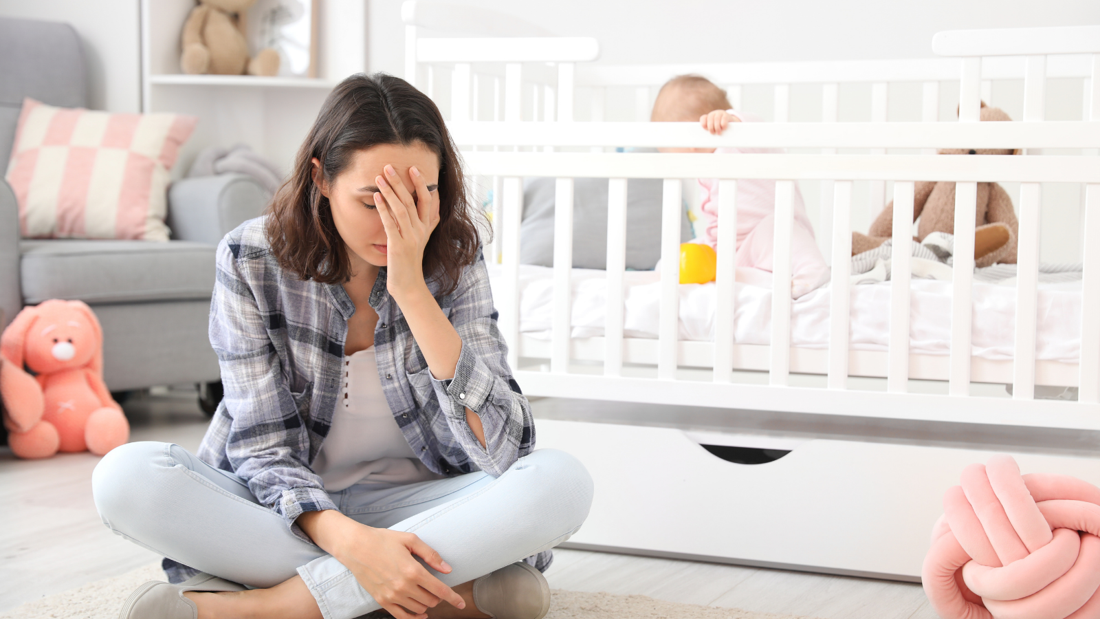 Mother sitting in front of baby crib